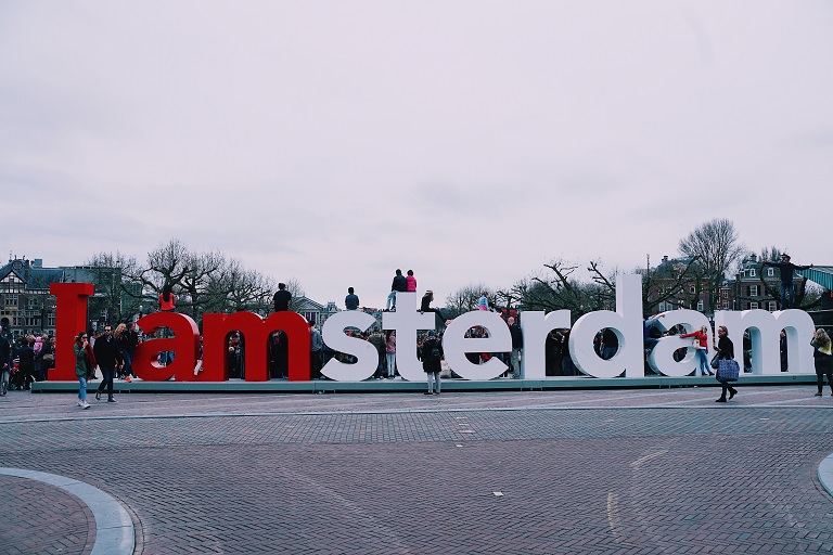 Amsterdam-skiltet i Amsterdam med mennesker, som sidder på det.