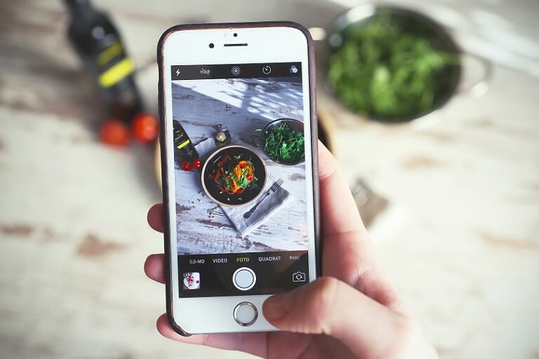 En smartphone som tager et billede af mad på et bord.